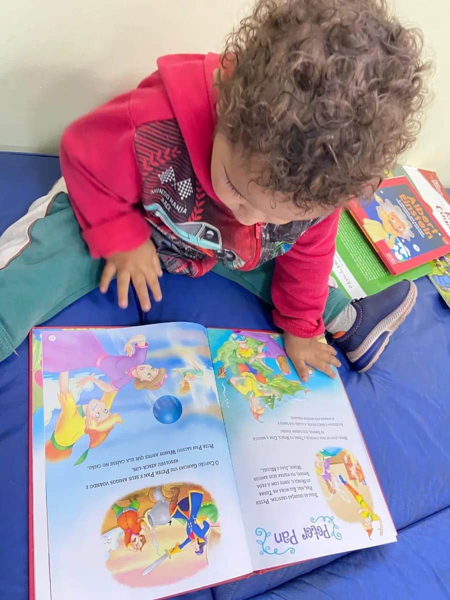 Criança pequena lendo um livro de histórias na sede