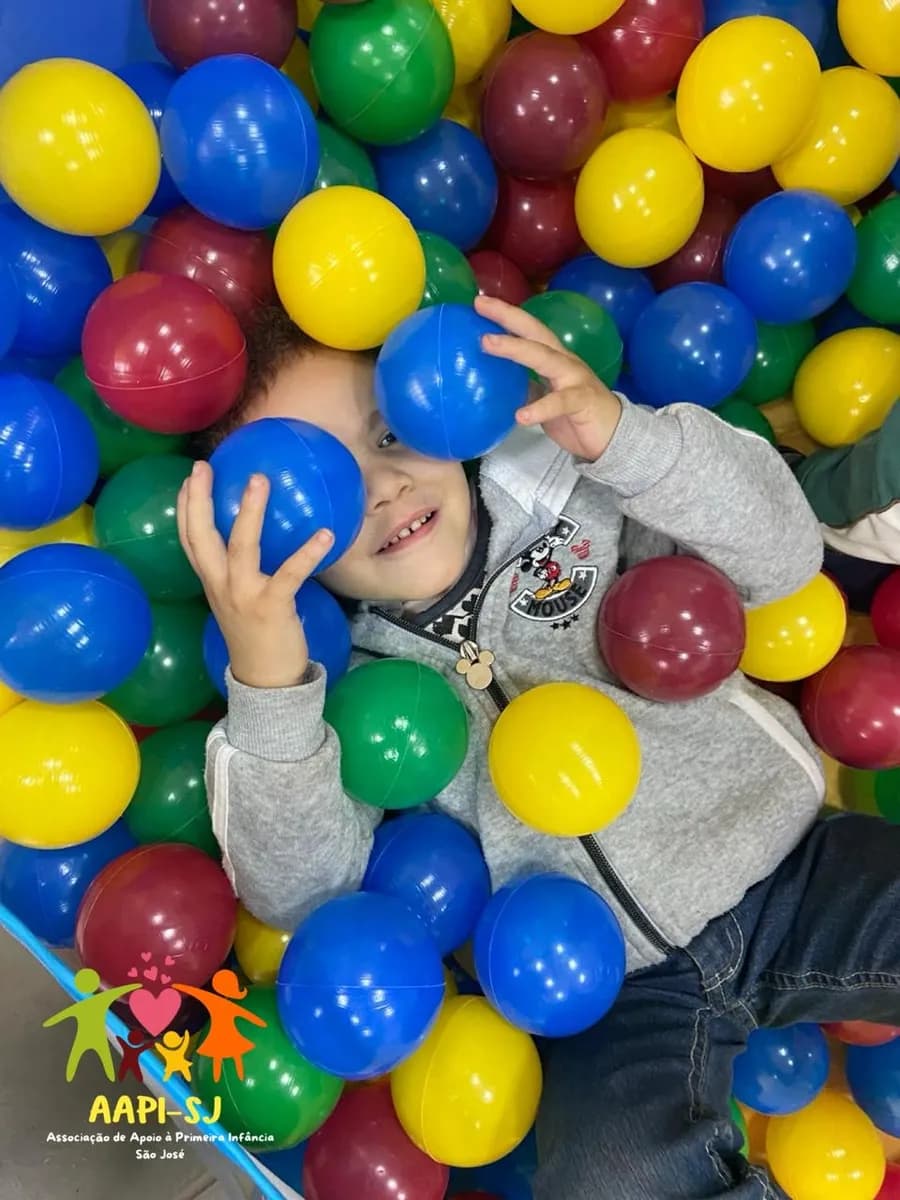 Menino sorrindo na piscina de bolinhas da AAPI-SJ