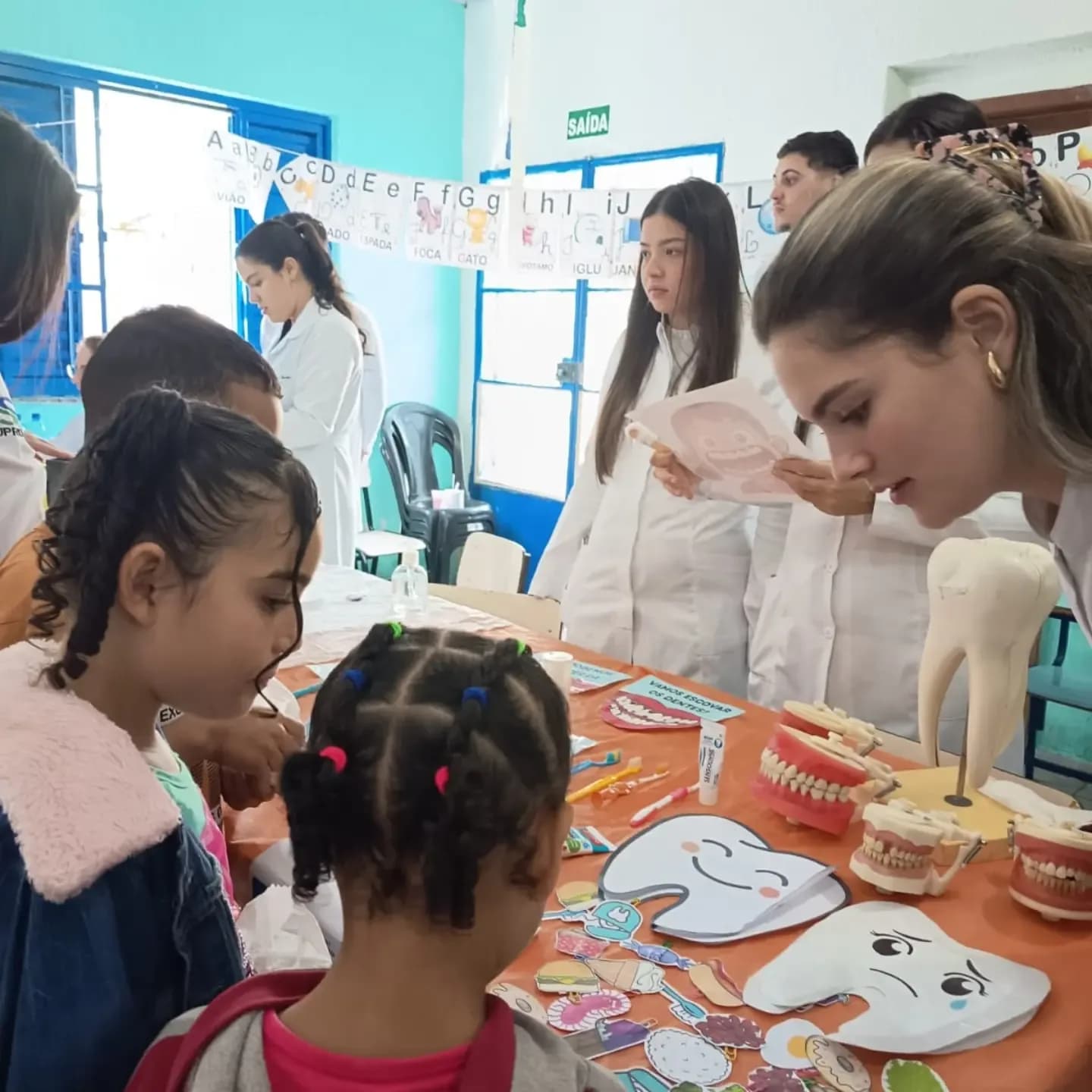 Estudantes de Odontologia ensinando escovação com modelos de dentes