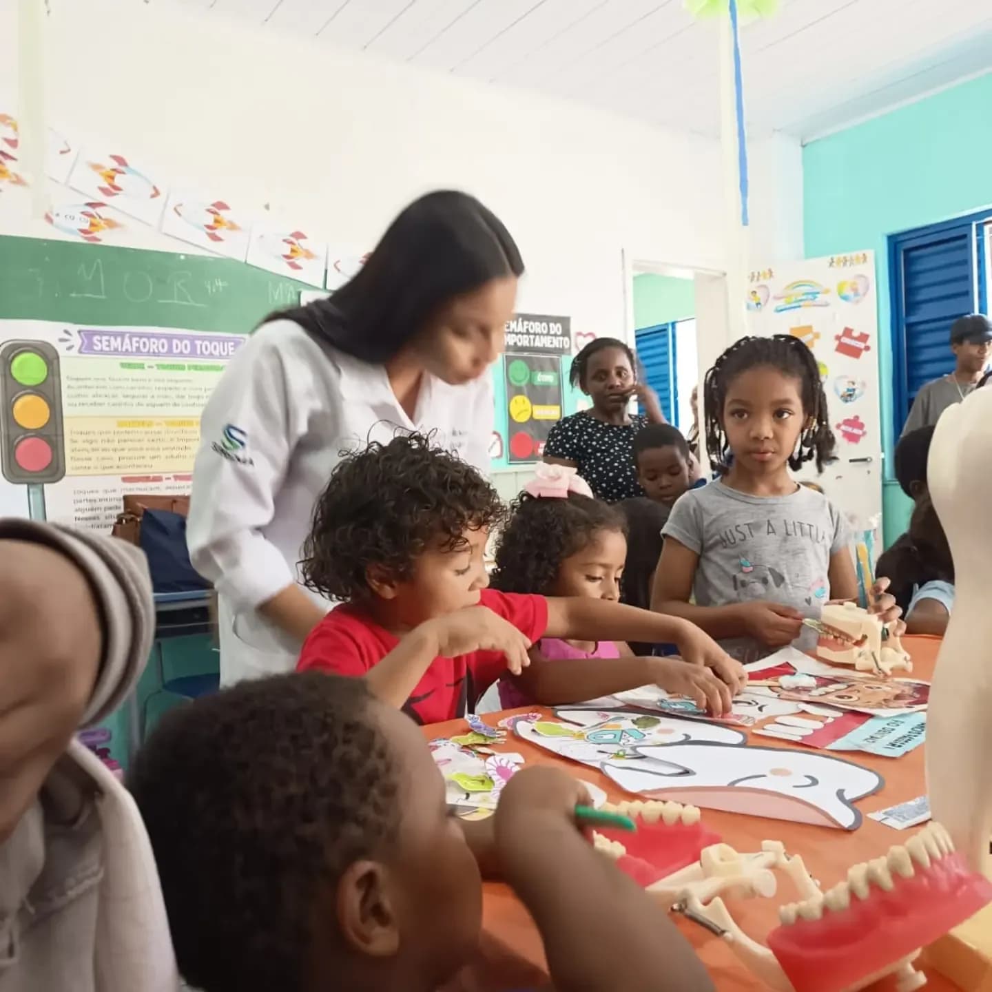 Criança aprendendo sobre saúde bucal com uma estudante