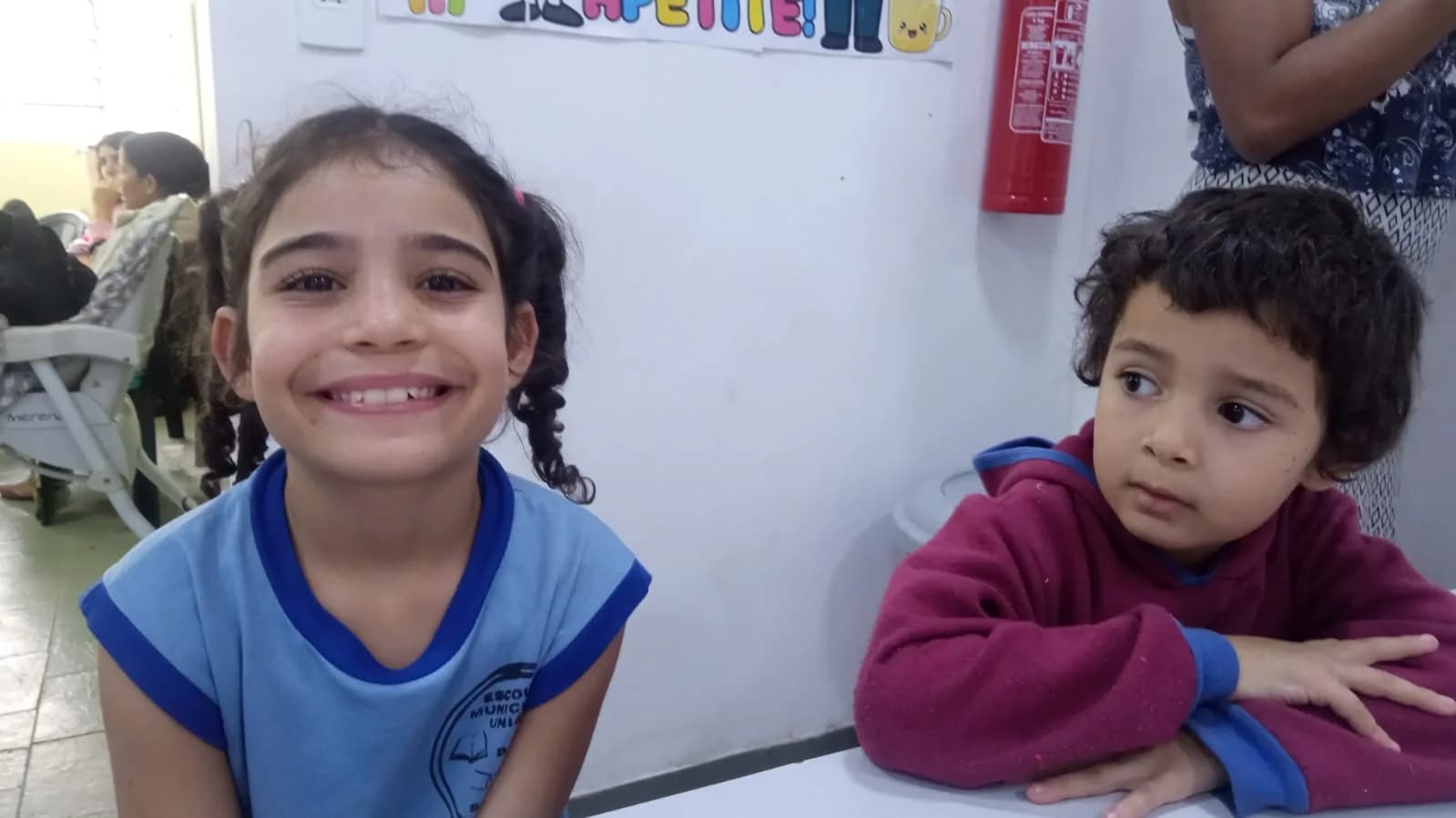 Crianças sorrindo durante a oficina de culinária no refeitório