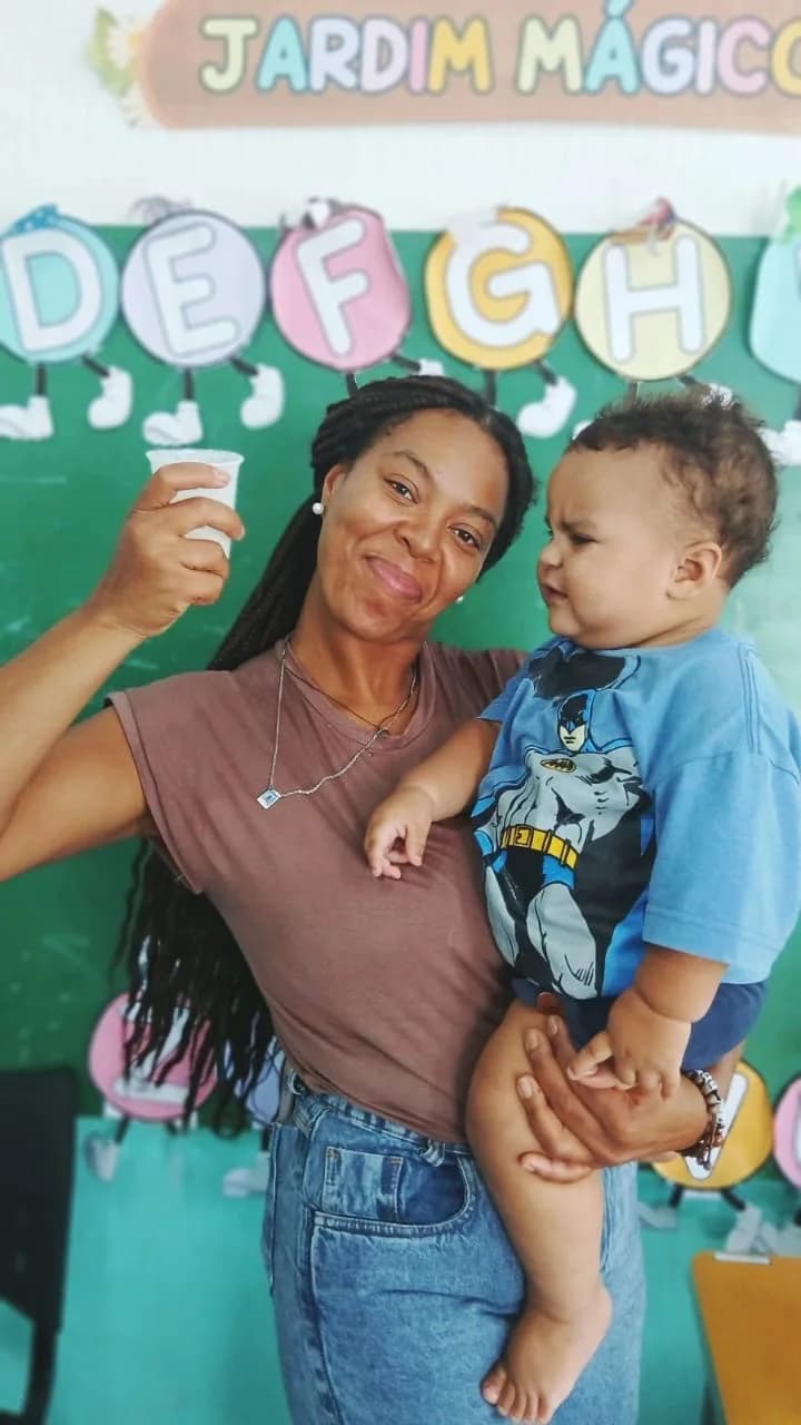 Voluntária com um bebê no colo, no Jardim Mágico