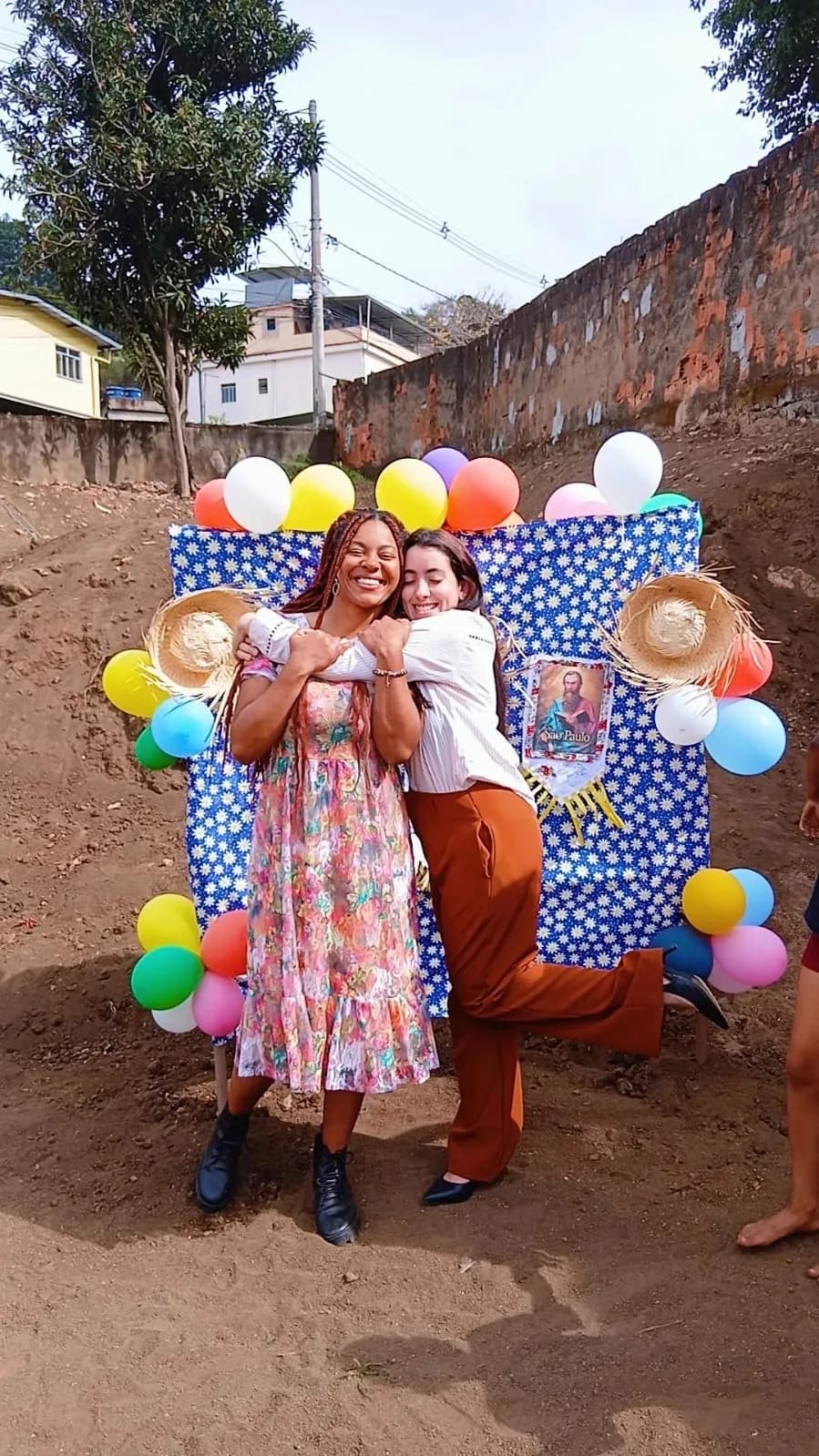 Equipe se abraçando no painel decorado com chapéus de palha