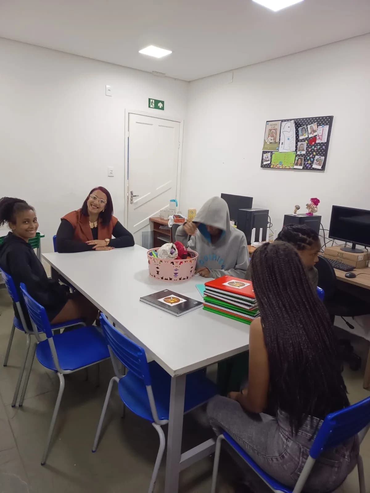 Educadora e adolescentes reunidos à mesa na oficina de vocações