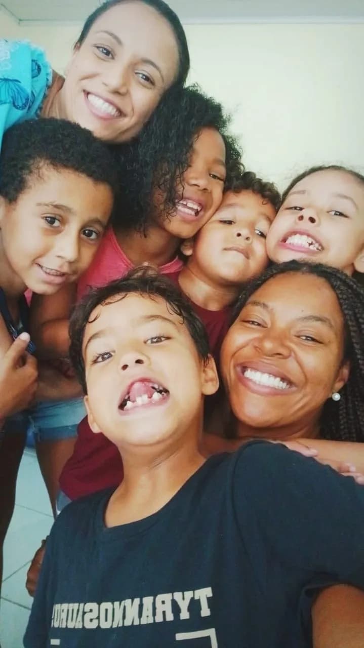 Equipe e crianças reunidas em um abraço coletivo