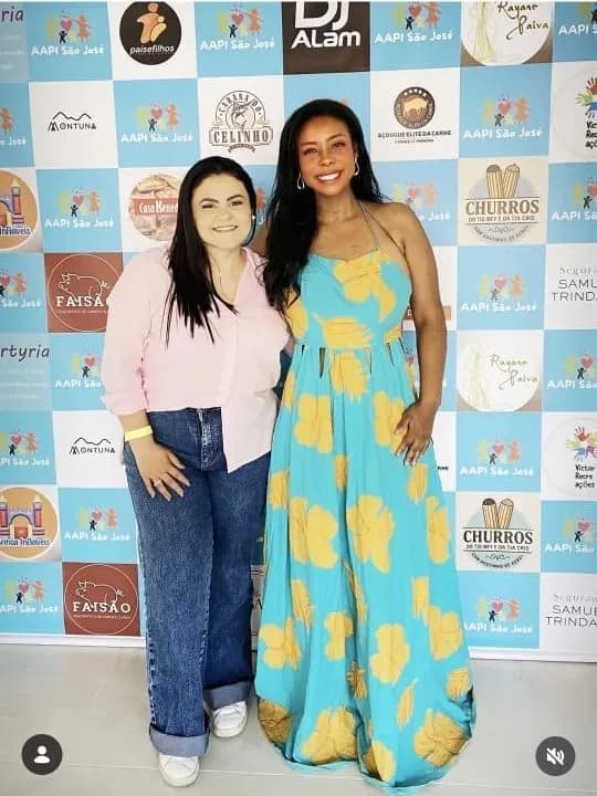 Liziene com uma convidada diante do painel da festa