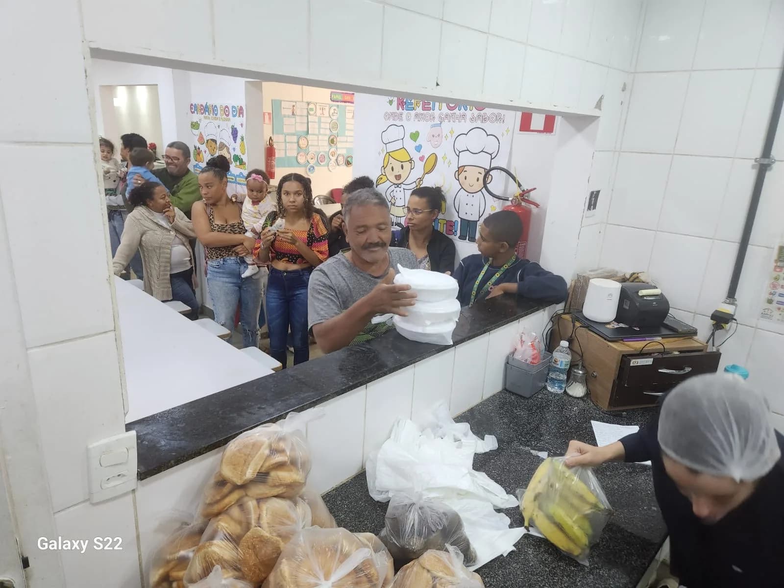 Voluntário separando as marmitas para entrega na janela da Cozinha Solidária