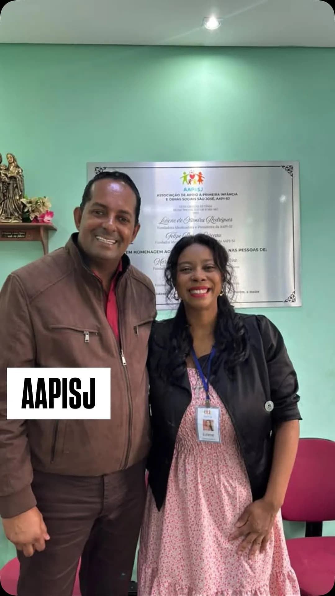 Visita à sede: a coordenadora da AAPI-SJ recebe um visitante diante da placa de inauguração.