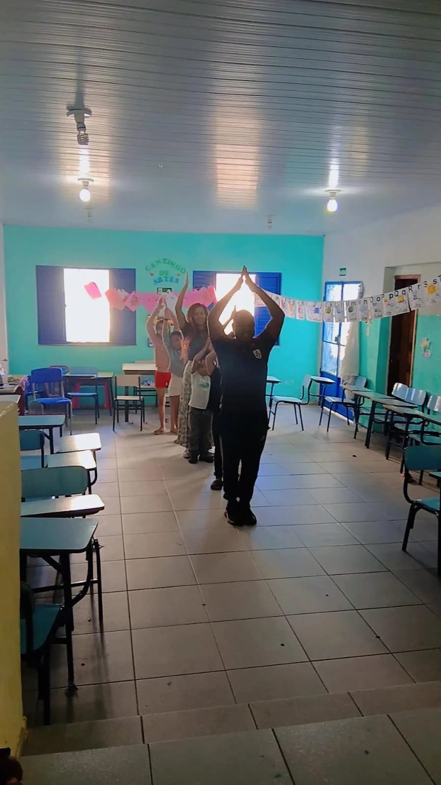 Crianças e o tio Adriano dançando juntos na oficina de Hip-Hop