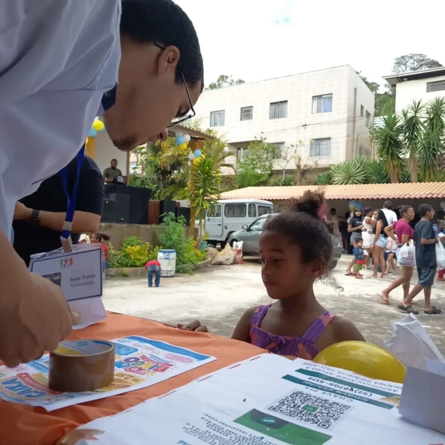 Estudante orientando uma criança na mesa de atendimentos