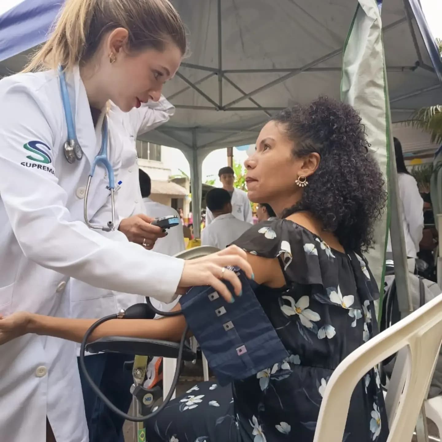 Estudante de saúde medindo a pressão de uma moradora