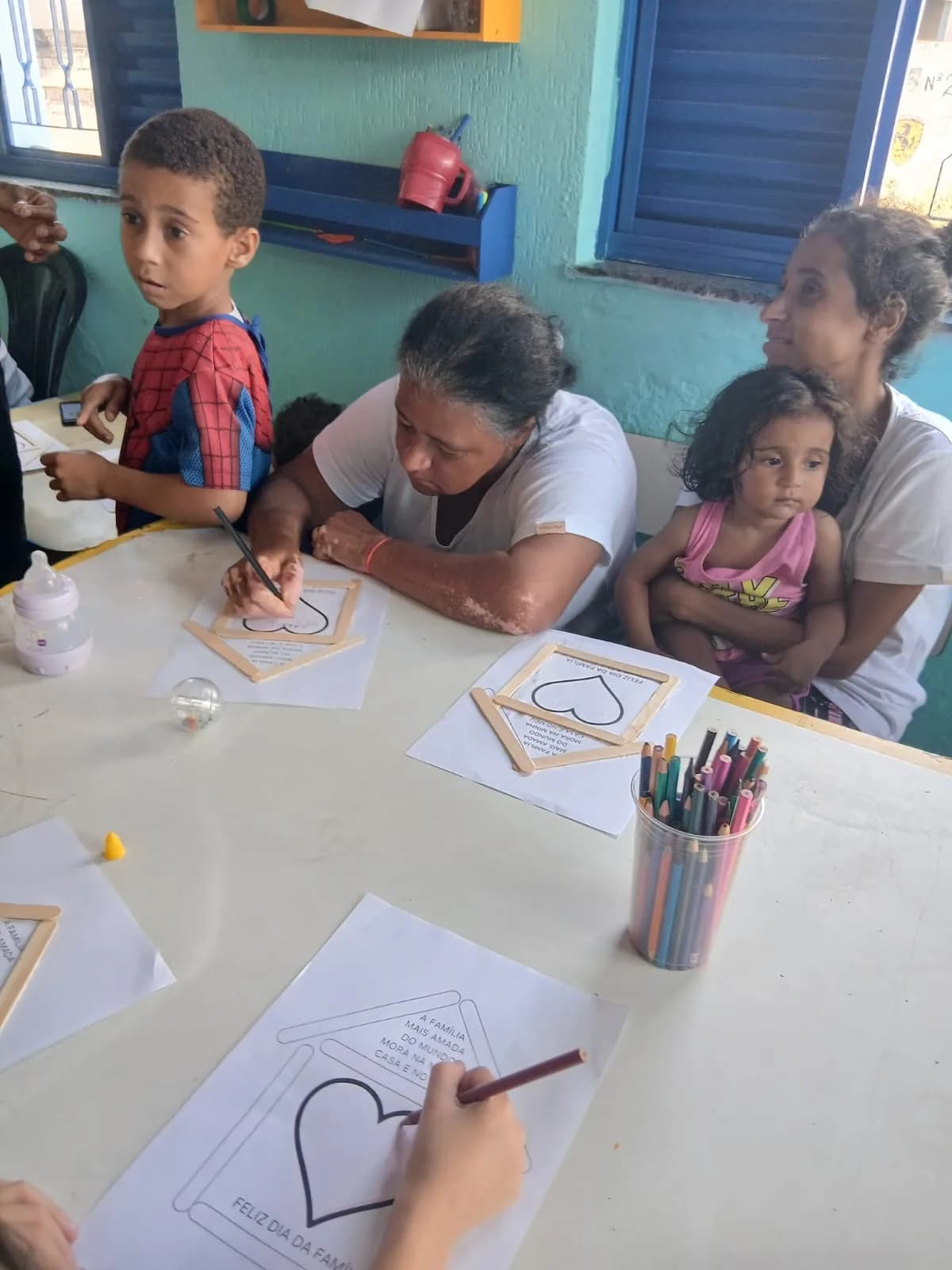 Mães e crianças fazendo o porta-retrato em formato de coração na Festa da Família