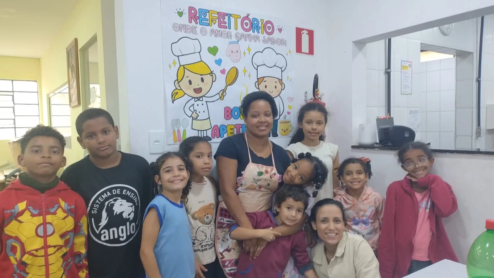 Tia Sabrina, cozinheira da AAPI-SJ, com as crianças no refeitório