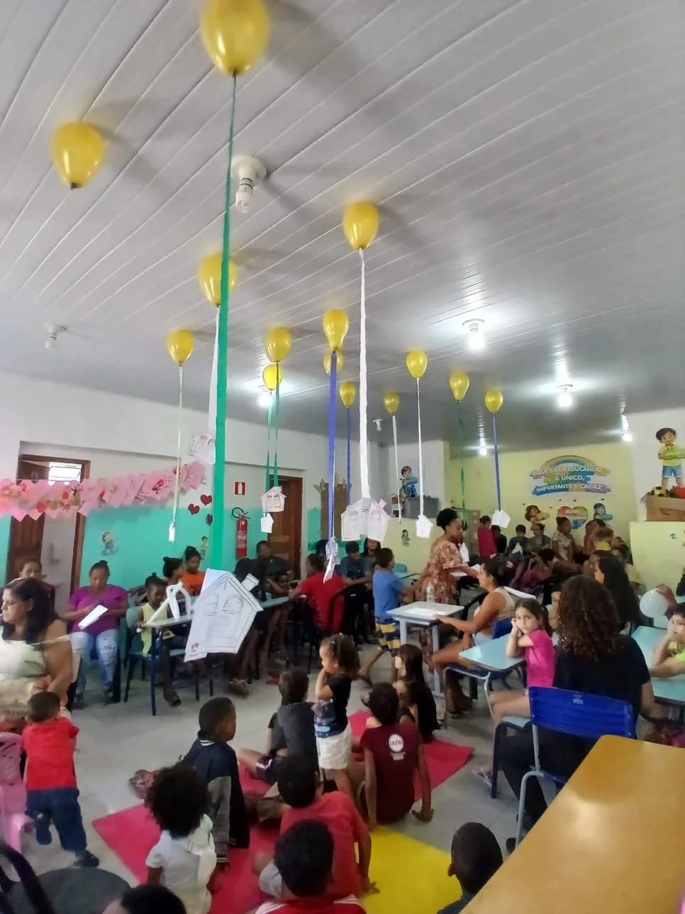 Crianças e famílias reunidas sob os balões da Festa da Família