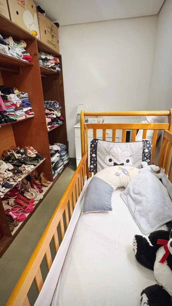 Prateleiras de roupas e sapatos organizados e berço no Cantinho da Mamãe e do Bebê