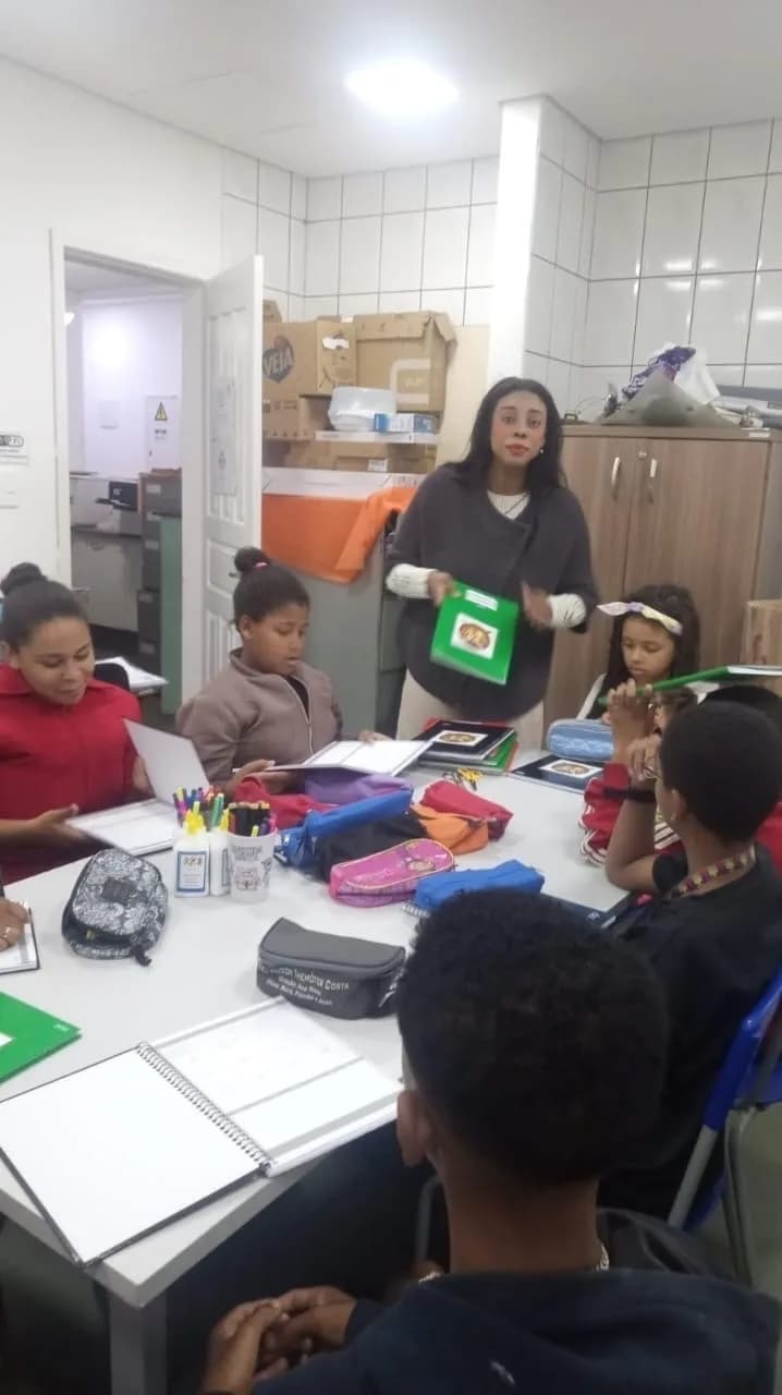 Educadora distribuindo materiais para as crianças e adolescentes