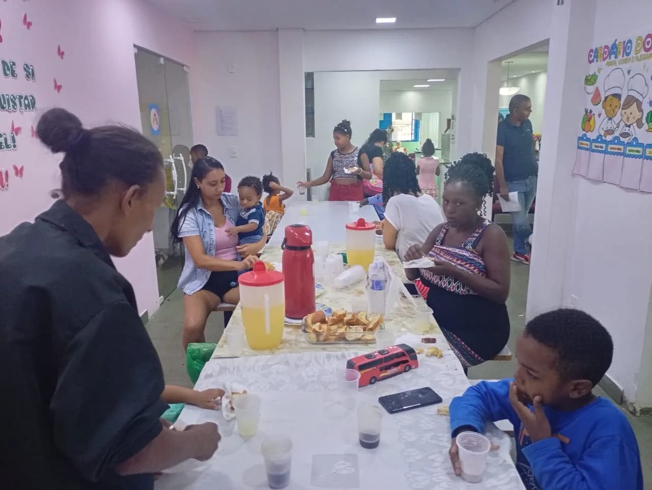 Famílias reunidas em volta da mesa no lanche da Cozinha Solidária