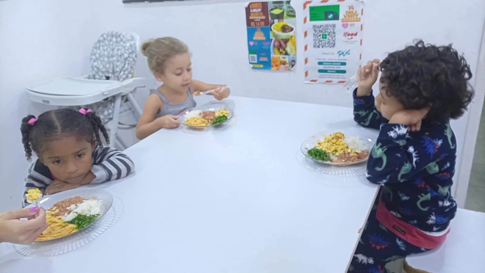 Crianças sentadas à mesa com pratos da Cozinha Solidária