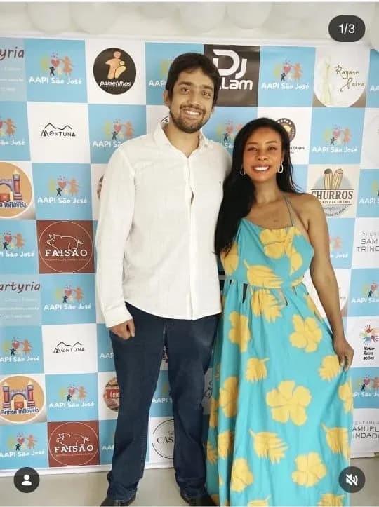 Felipe e Liziene diante do painel de patrocinadores da Feijoada pela Infância