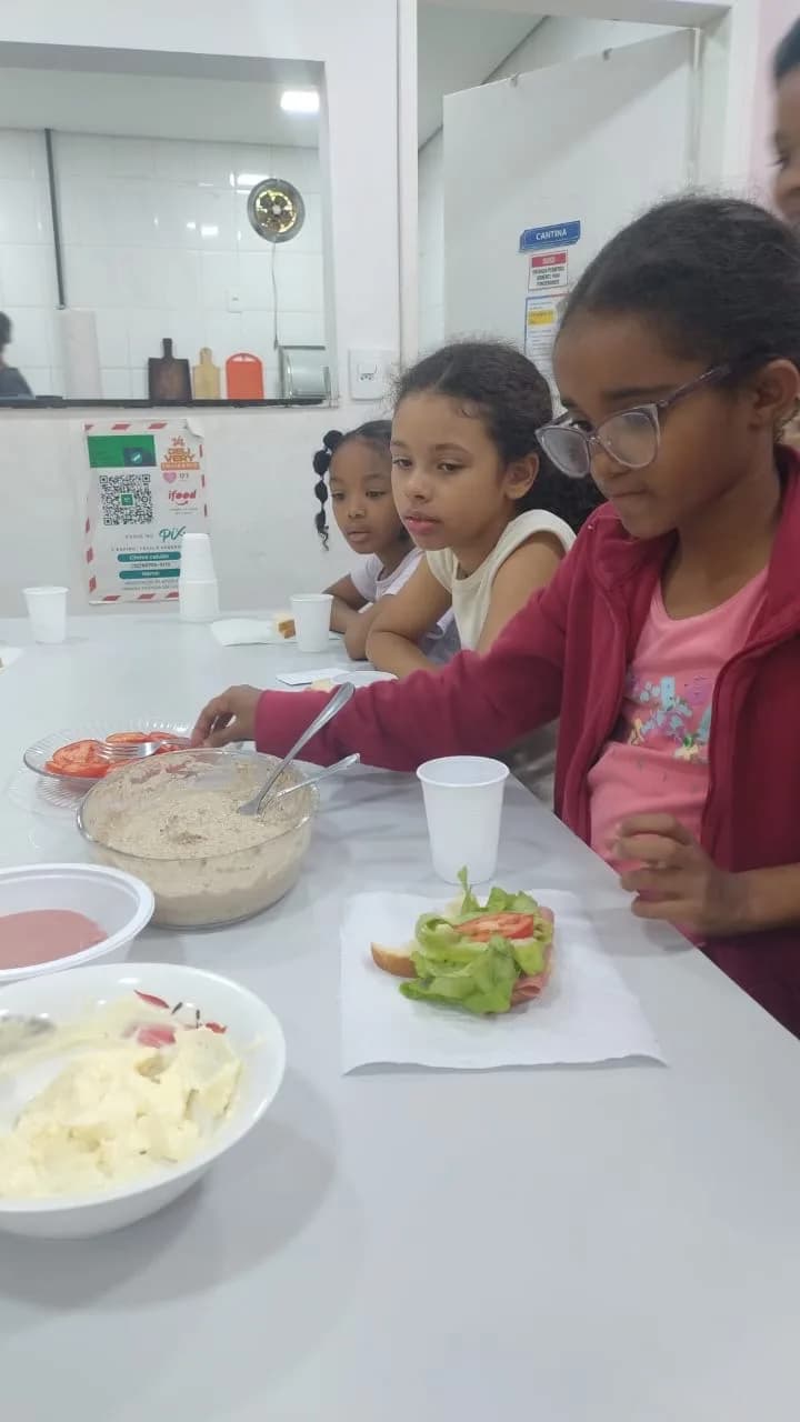 Crianças montando o sanduíche com alface e tomate