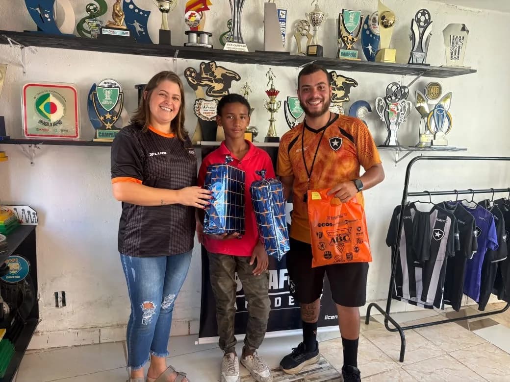 Vítor Hugo recebendo os presentes da bolsa de futebol, ao lado da equipe do Botafogo do bairro Grama