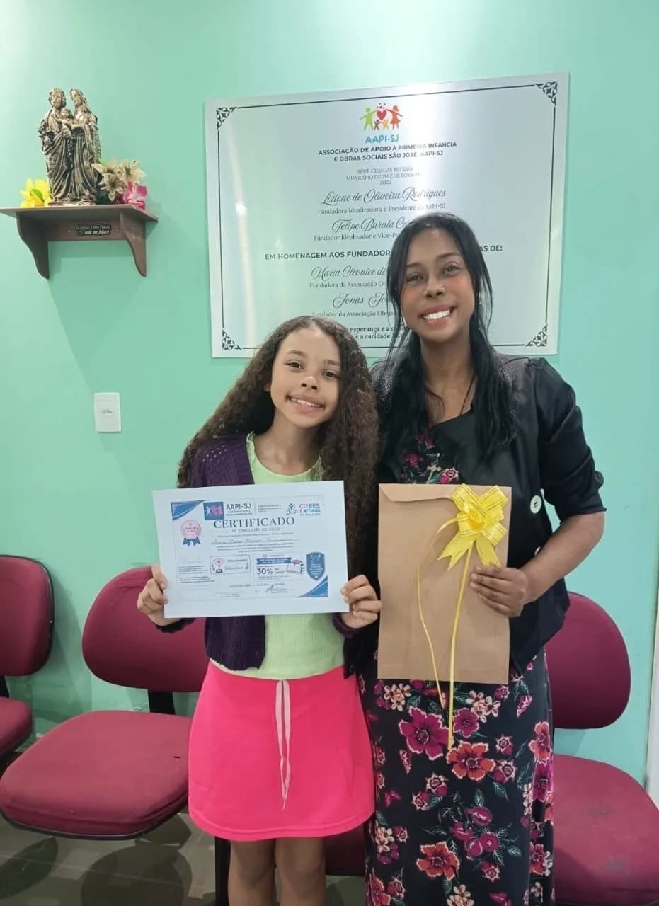 Adolescente recebendo o certificado de conclusão de ciclo do programa Cores e Ritmos