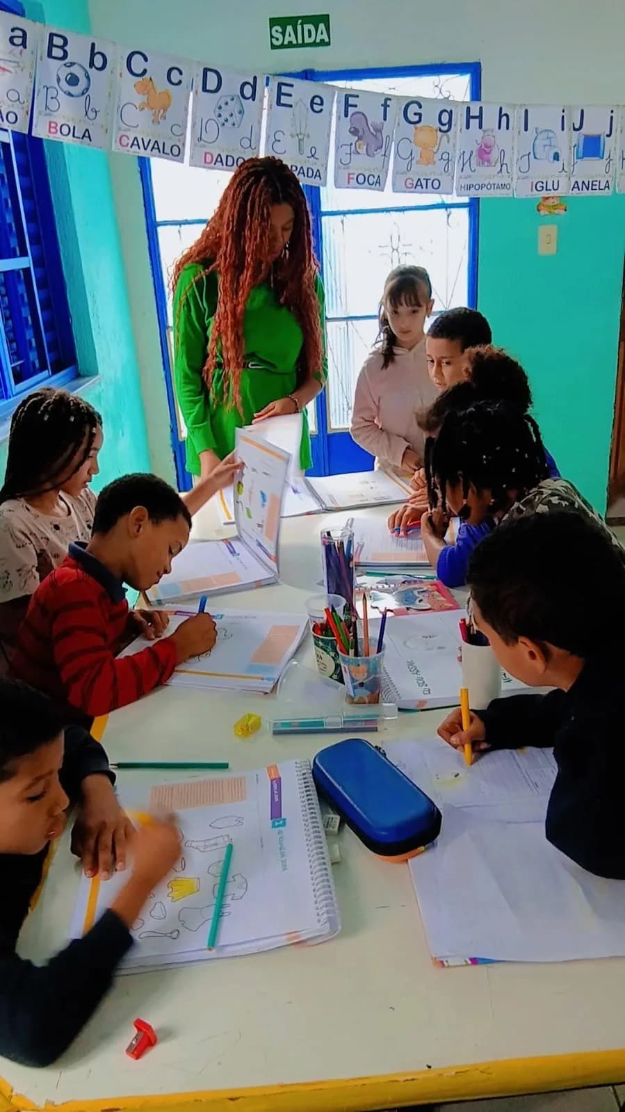 Educadora auxiliando as crianças nas atividades do contraturno escolar