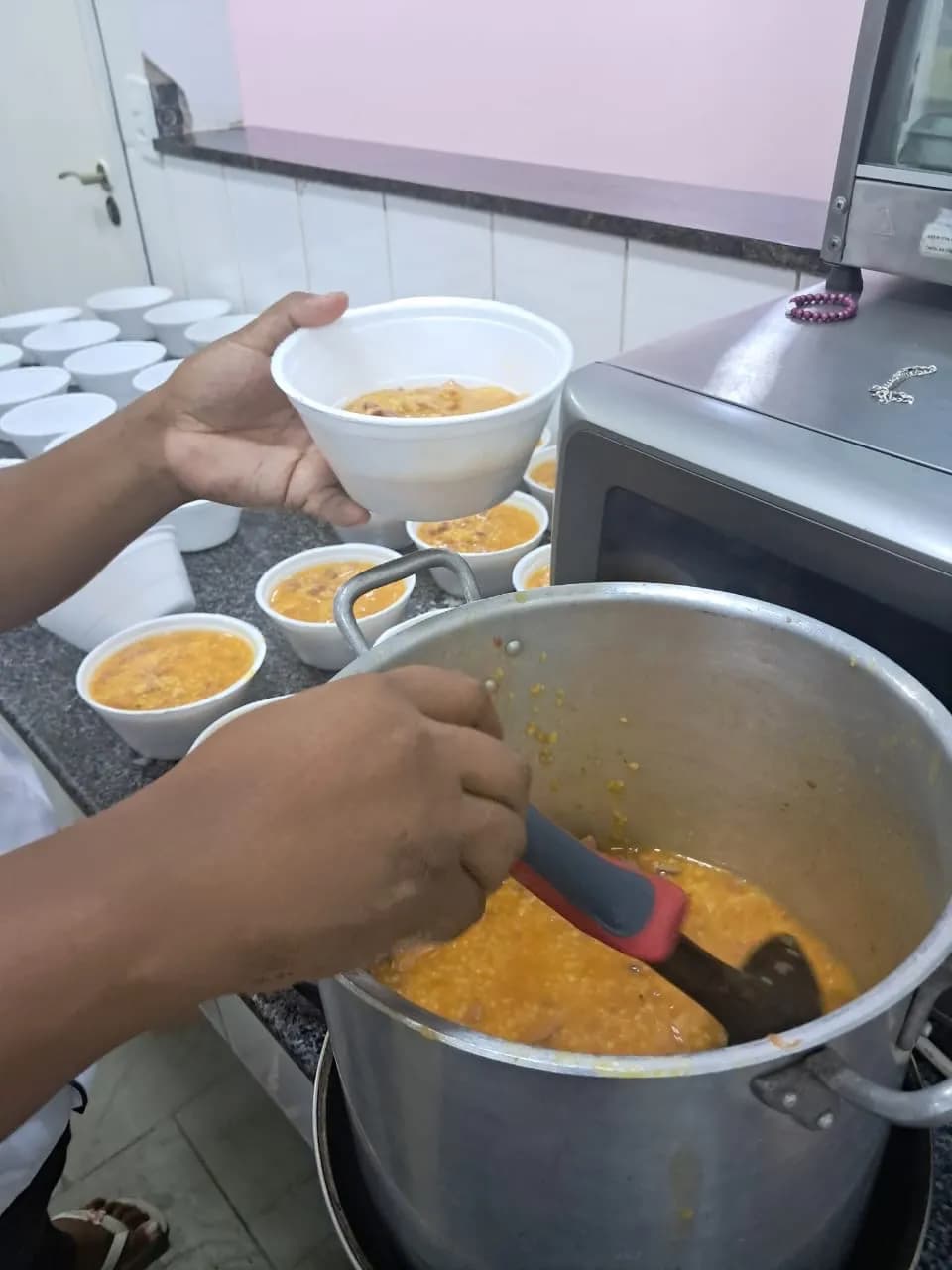 Sopa sendo servida em potes na cozinha da AAPI-SJ