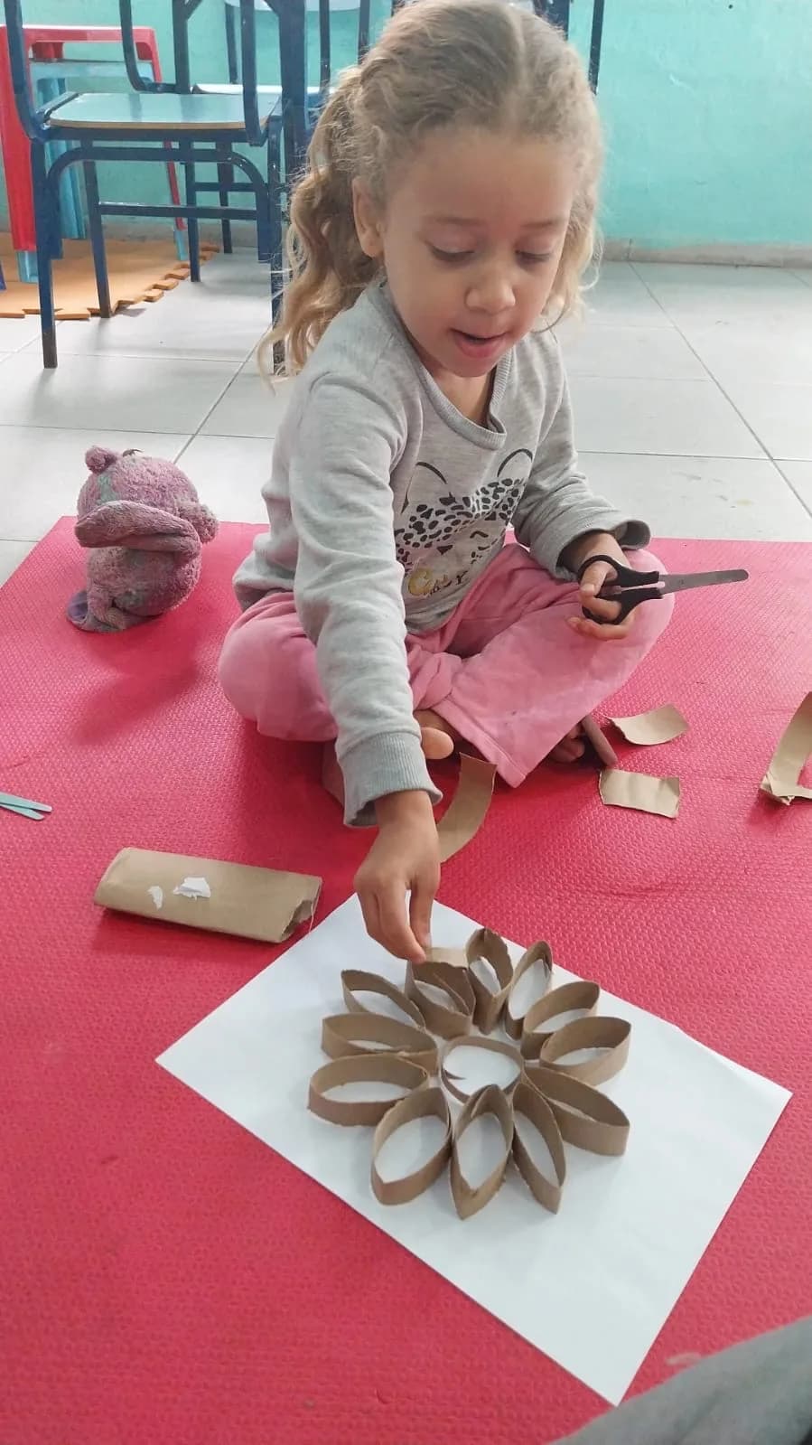 Criança montando uma flor com rolos de papelão