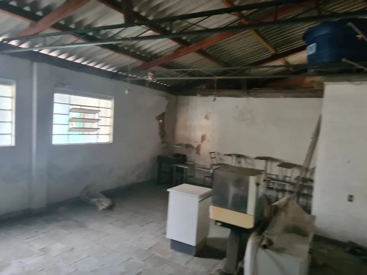 Interior vazio da estrutura antiga da sede, com telhado aparente e móveis antigos