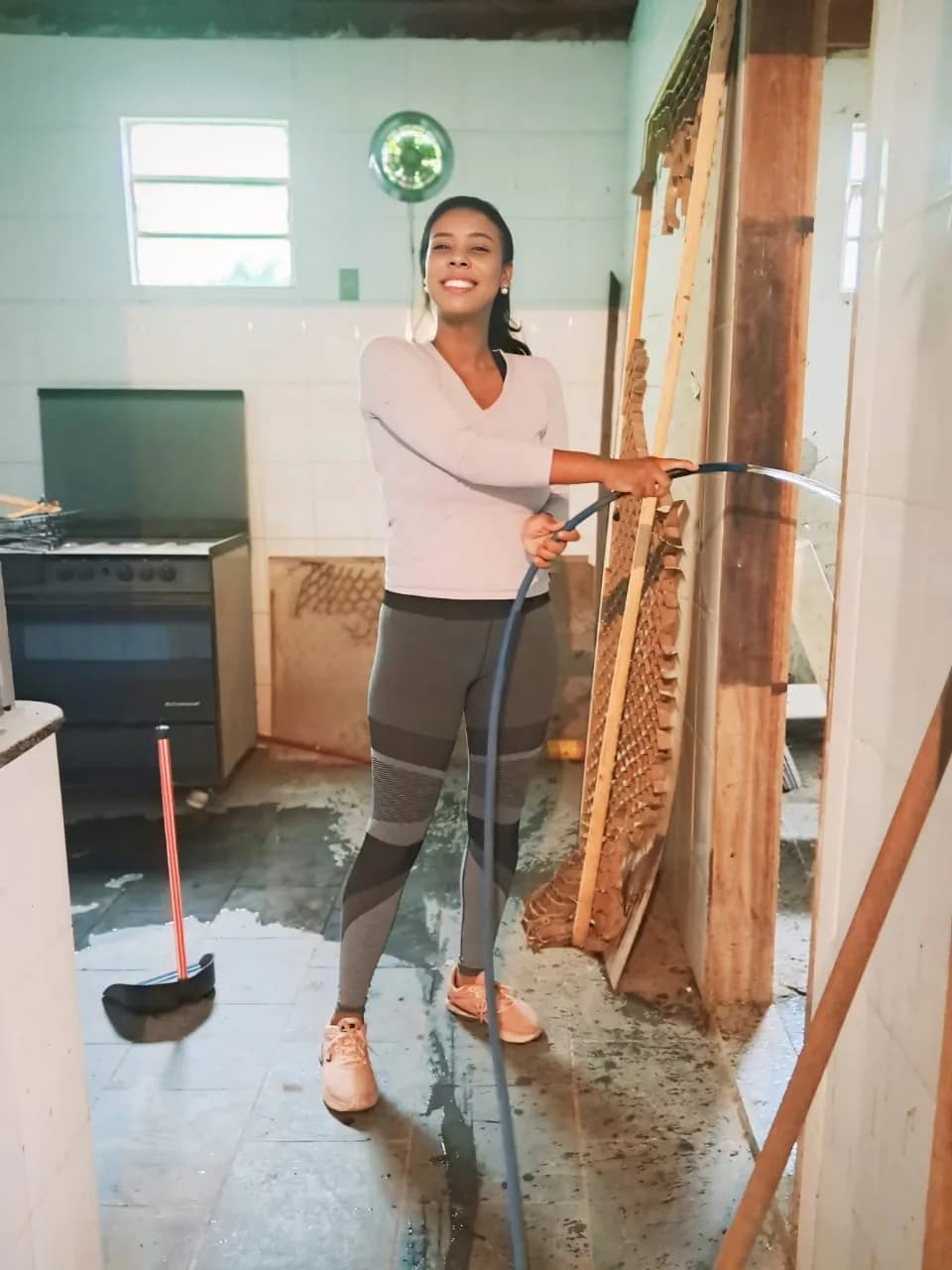 Voluntária lavando a cozinha com mangueira